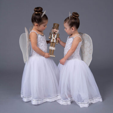 Two young girl in angle costumes with nutcracker prop