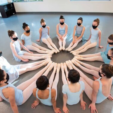Young teen girls sitting on the floor with toes points toward each other