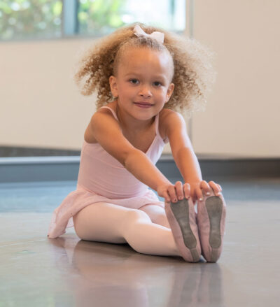Frankie, little girl, sitting on the floor holding her toes.